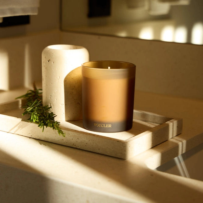 A candle on a tray next to a mirror, creating a cozy and elegant atmosphere.