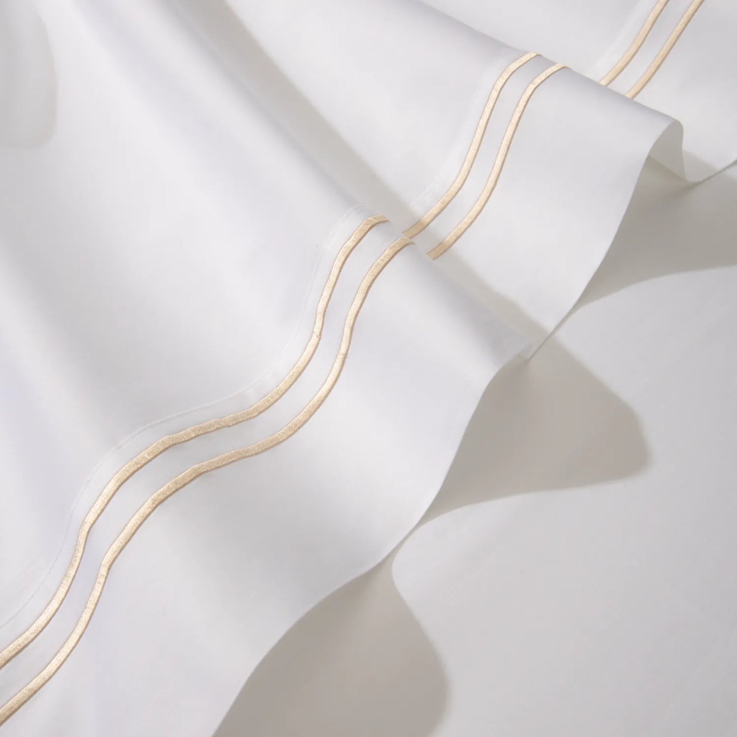 Lençol de cama na cor branca com detalhe dourado