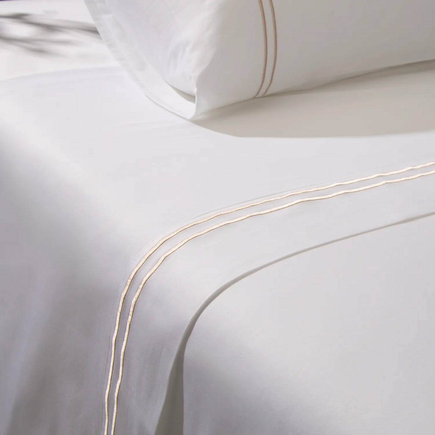 Lençol de cama na cor branca com detalhe dourado