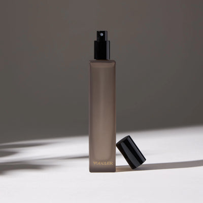 Voucler room spray bottle in dark gray with a black cap next to the bottle, highlighting the minimalist packaging on a neutral background.
