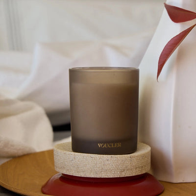 A candle on a decorative tray beside a soft white pillow, creating a cozy and inviting atmosphere.