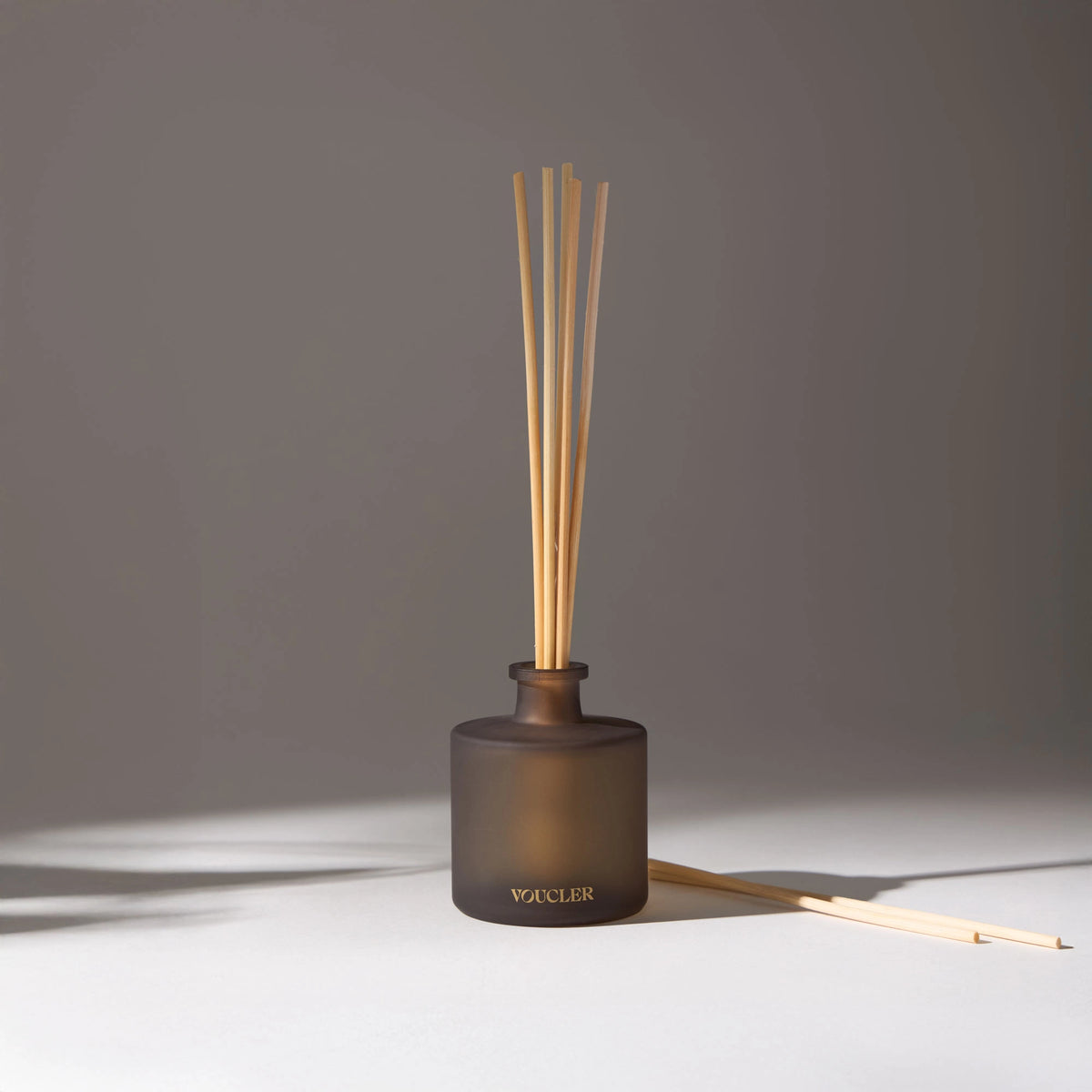 A room diffuser with wooden sticks in a dark, decorative and aromatic vase, ideal for creating a relaxing and elegant atmosphere.