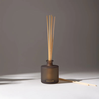 A room diffuser with wooden sticks in a dark, decorative and aromatic vase, ideal for creating a relaxing and elegant atmosphere.