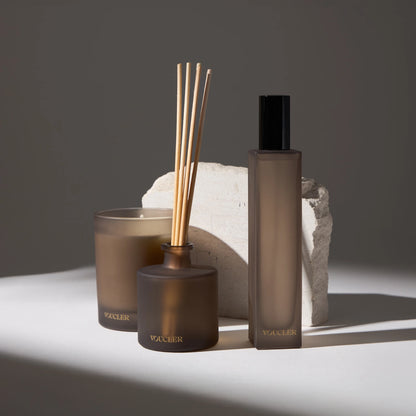 Set of decorative items and air fresheners from the Voucler brand, including a candle, aroma diffuser and spray, with a minimalist background and soft lighting.