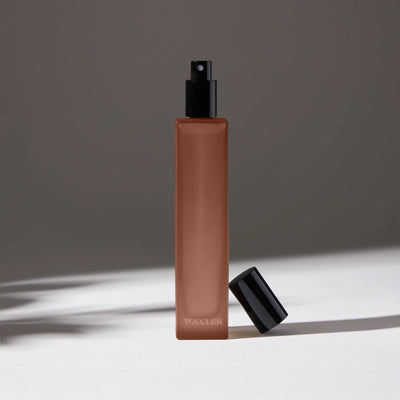 Voucler room spray bottle in dark pink with a black cap next to the bottle, highlighting the minimalist packaging on a neutral background.