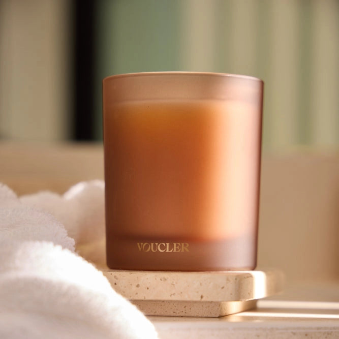 A candle next to a towel on a counter, creating a cozy and relaxing atmosphere.