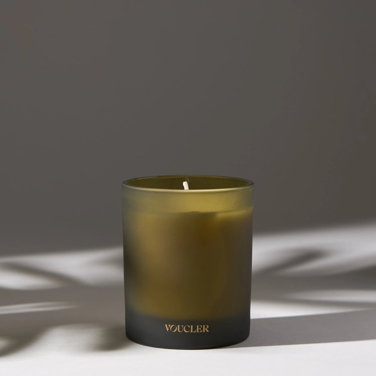 A lit candle on a table casting a soft shadow, creating a warm and inviting atmosphere.