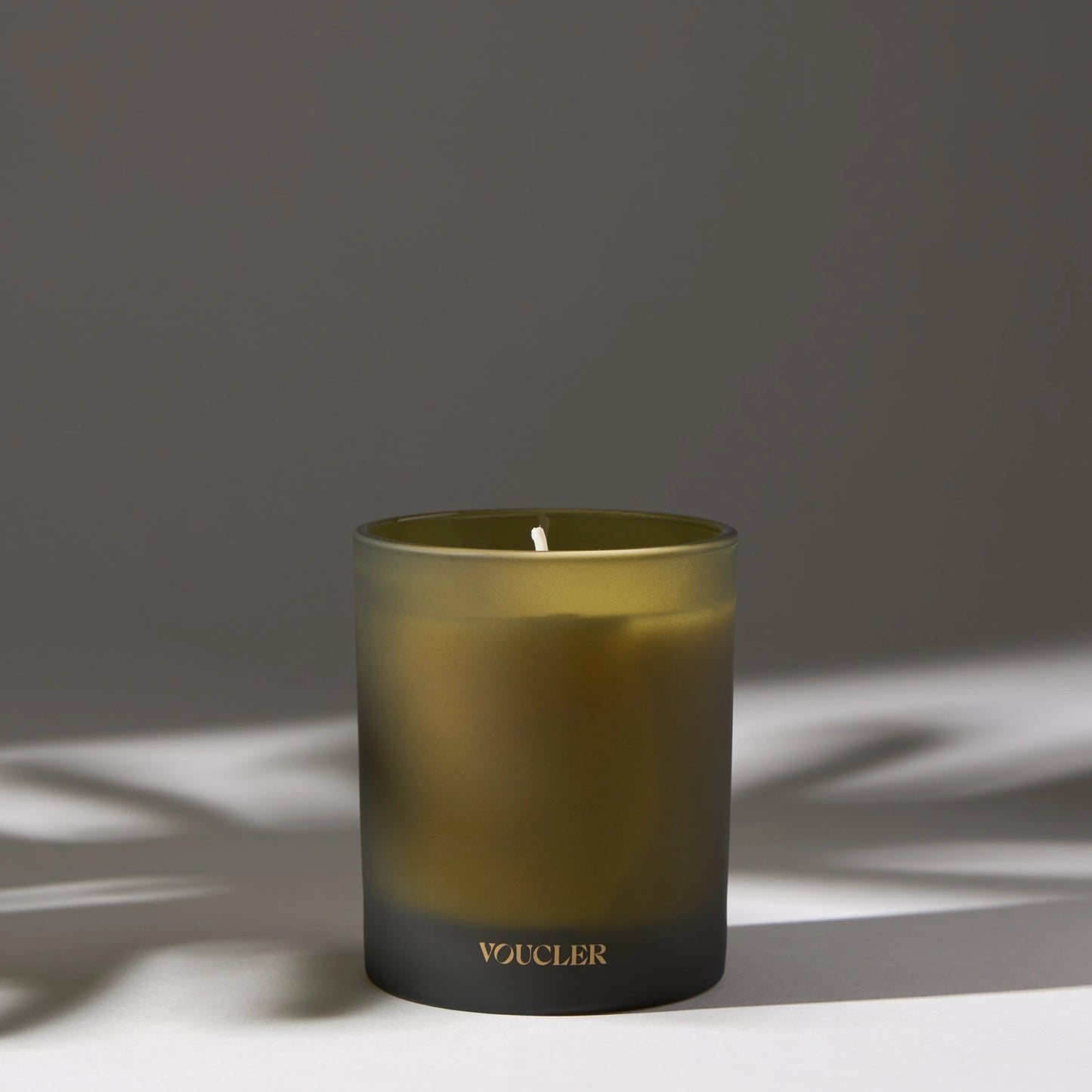 A lit candle on a table casting a soft shadow, creating a warm and inviting atmosphere.