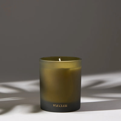 A lit candle on a table casting a soft shadow, creating a warm and inviting atmosphere.