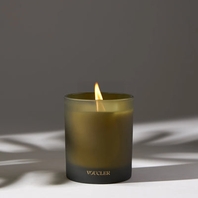 A lit candle on a table casting a soft shadow, creating a warm and inviting atmosphere.