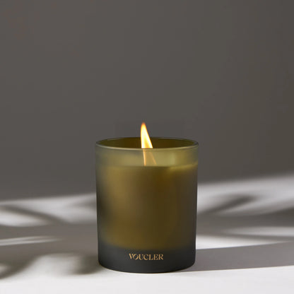 A lit candle on a table casting a soft shadow, creating a warm and inviting atmosphere.