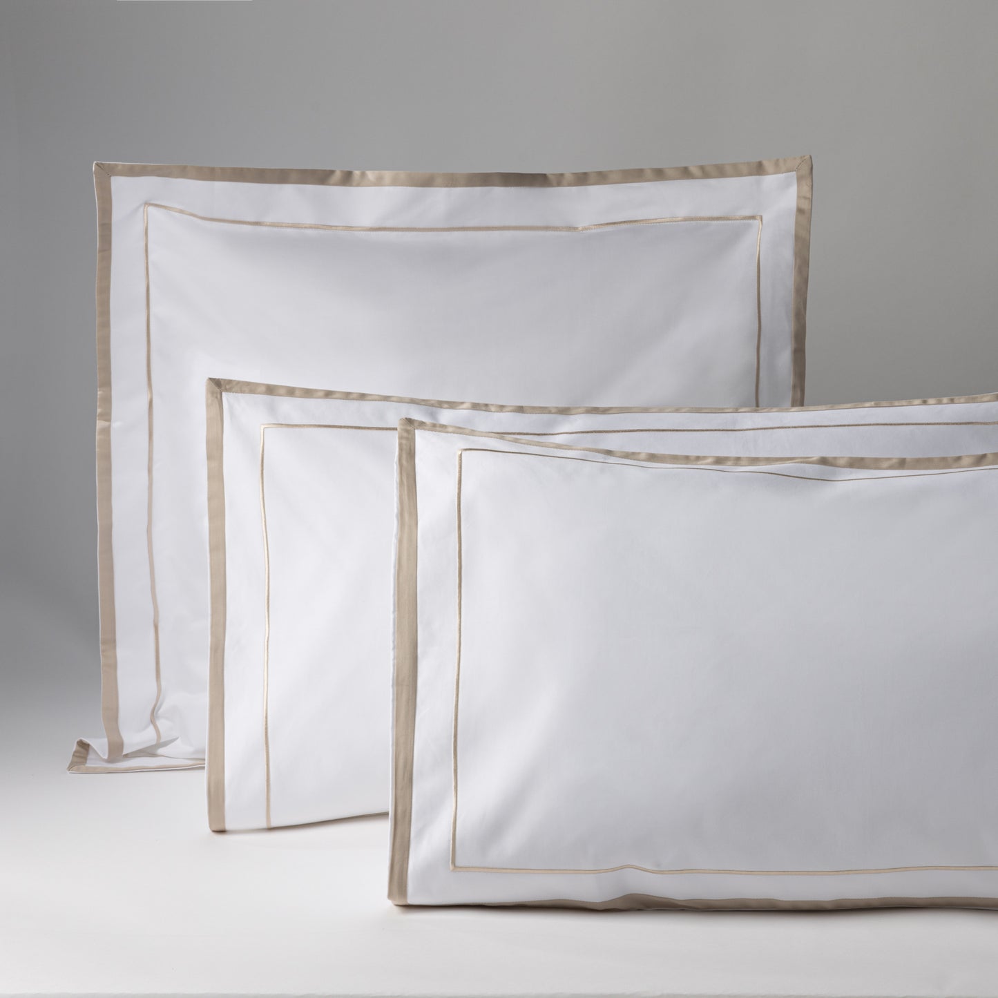 Set of white pillowcases with golden details, perfect for elegant decoration and comfort in bed.