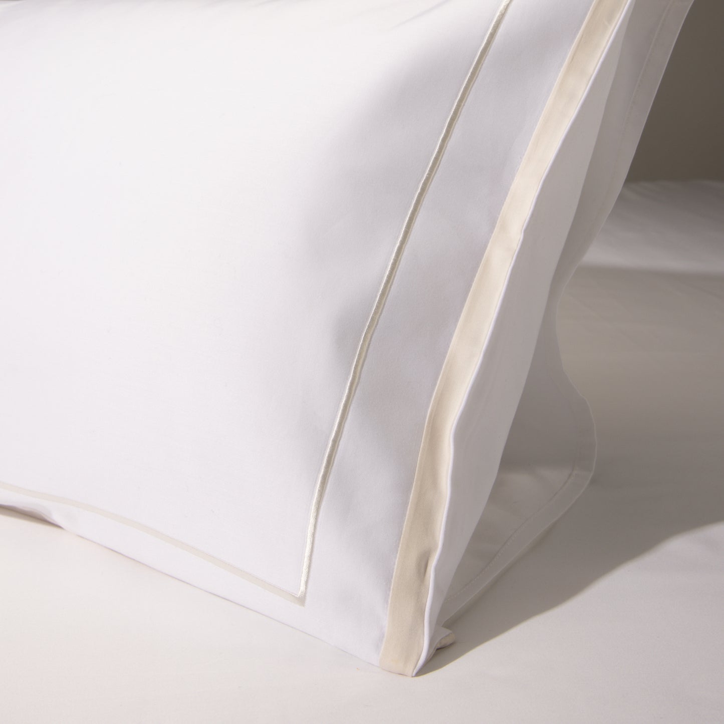 Detail of the golden stripes and white fabric of the Heaven Sateen pillowcase, conveying sophistication.