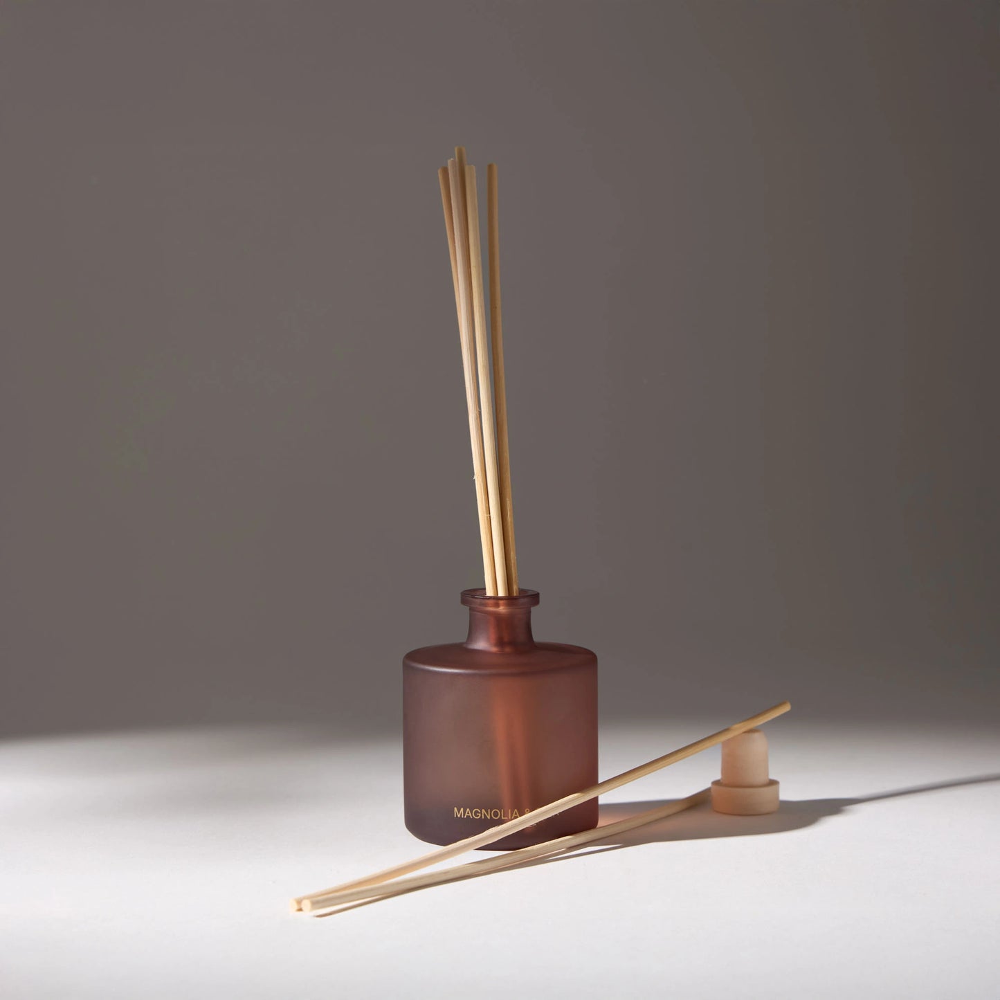 Aroma diffuser with wooden sticks in a brown ceramic pot by VOUCLER, decorative and aromatic for elegant rooms.