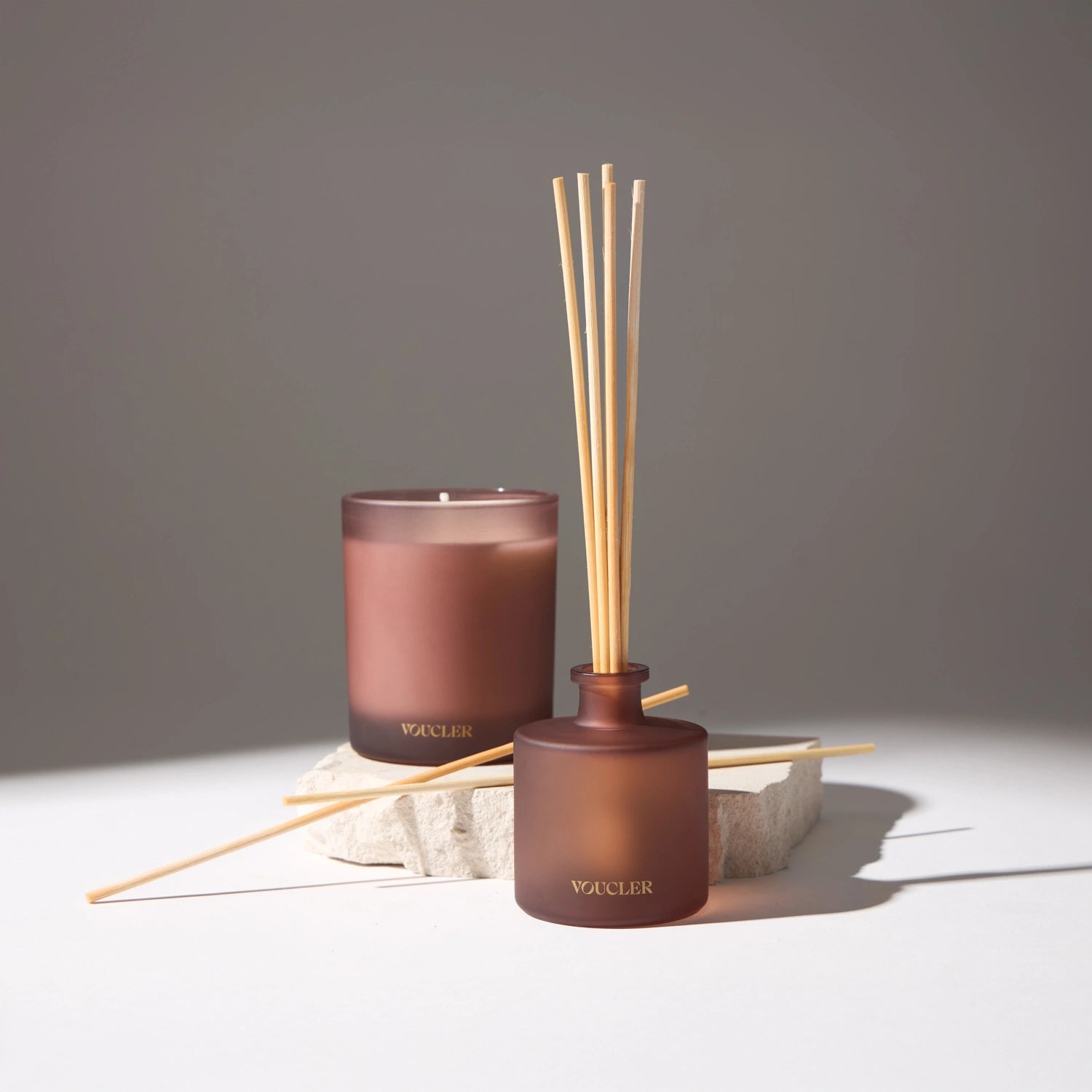 Voucler brand aroma diffuser with scented candle in dark pink frosted glass, decorating a space with an elegant and sophisticated touch.