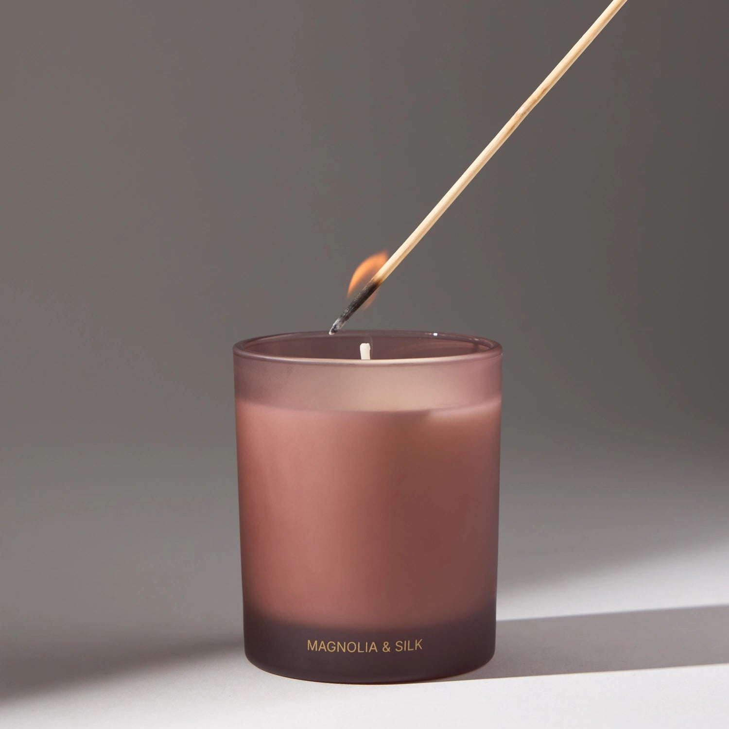 Decorative candle in pink by VOUCLER, with an elegant design, on a light background with soft shadows around it, ideal for decorating rooms.