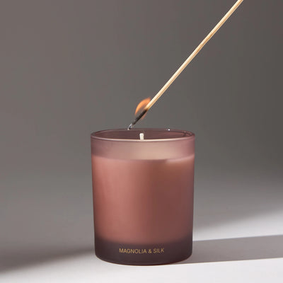 Decorative candle in pink by VOUCLER, with an elegant design, on a light background with soft shadows around it, ideal for decorating rooms.