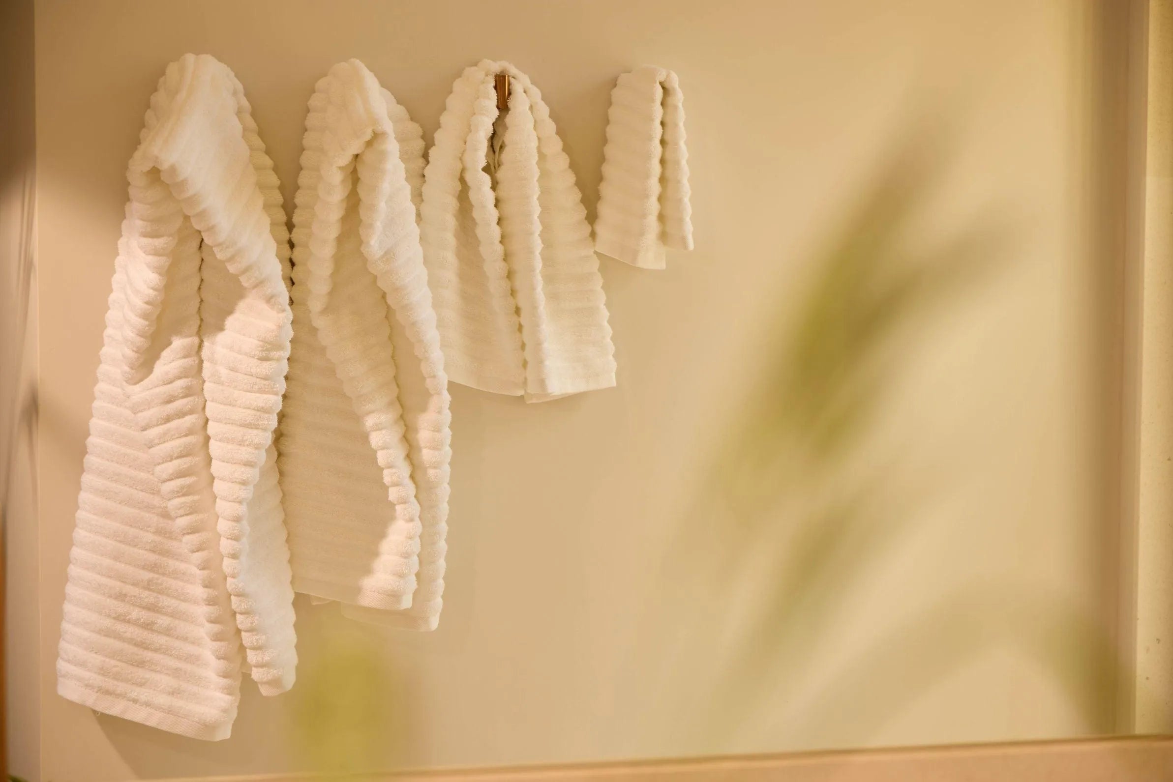 White bath towels hang on a wall rack, creating a cozy space, with the soft, clean texture of the fabric standing out.
