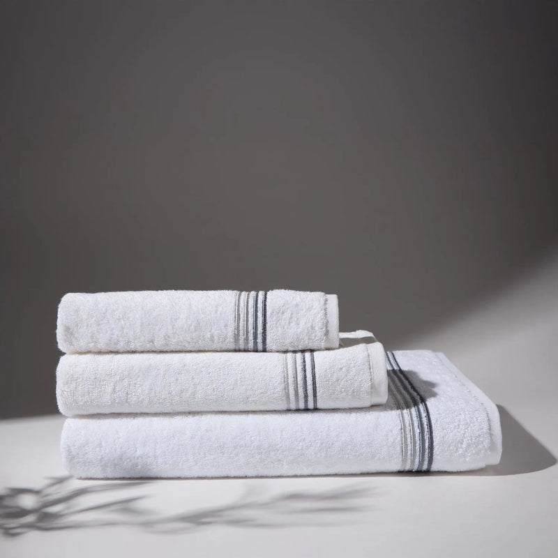 Image of thre gray towels stacked on top of each other, with a soft gray background, conveying a feeling of cleanliness and care for hygiene.