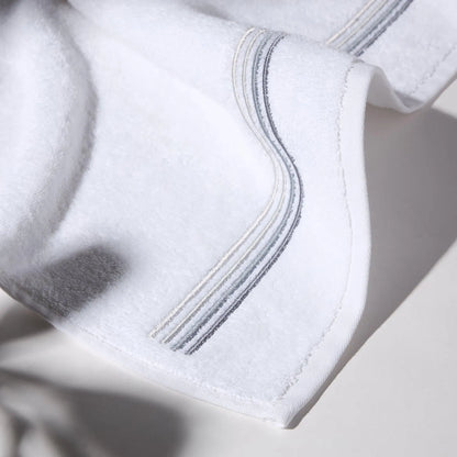 Detailed image of the stitching of a gray towel on a white surface, conveying a feeling of cleanliness and care for hygiene.