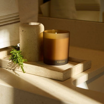 A decorative candle on a tray, placed next to a towel, suggesting a welcoming and relaxing space.