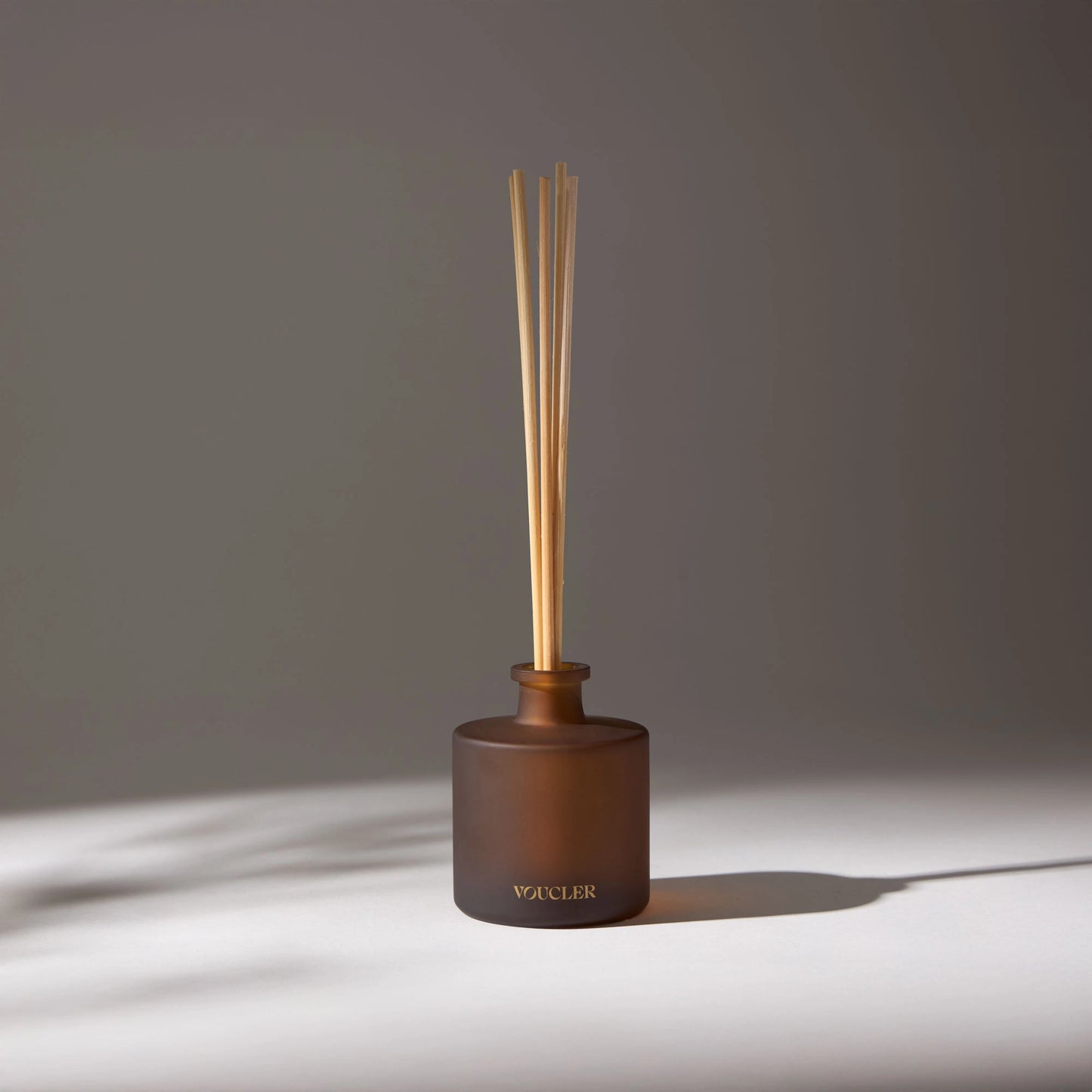 Aroma diffuser with wooden sticks and a brown glass bottle, decorating a room with soft lighting.