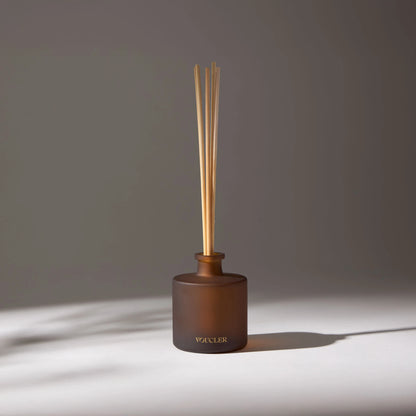 Aroma diffuser with wooden sticks and a brown glass bottle, decorating a room with soft lighting.