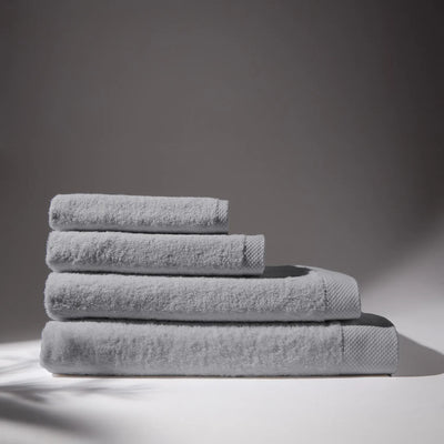 Image of four gray towels stacked on top of each other, with a soft gray background, conveying a feeling of cleanliness and care for hygiene.