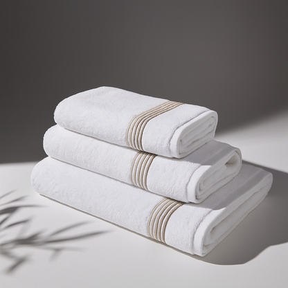 Set of folded white towels with beige stripes on a neutral background, conveying a sense of cleanliness and comfort.