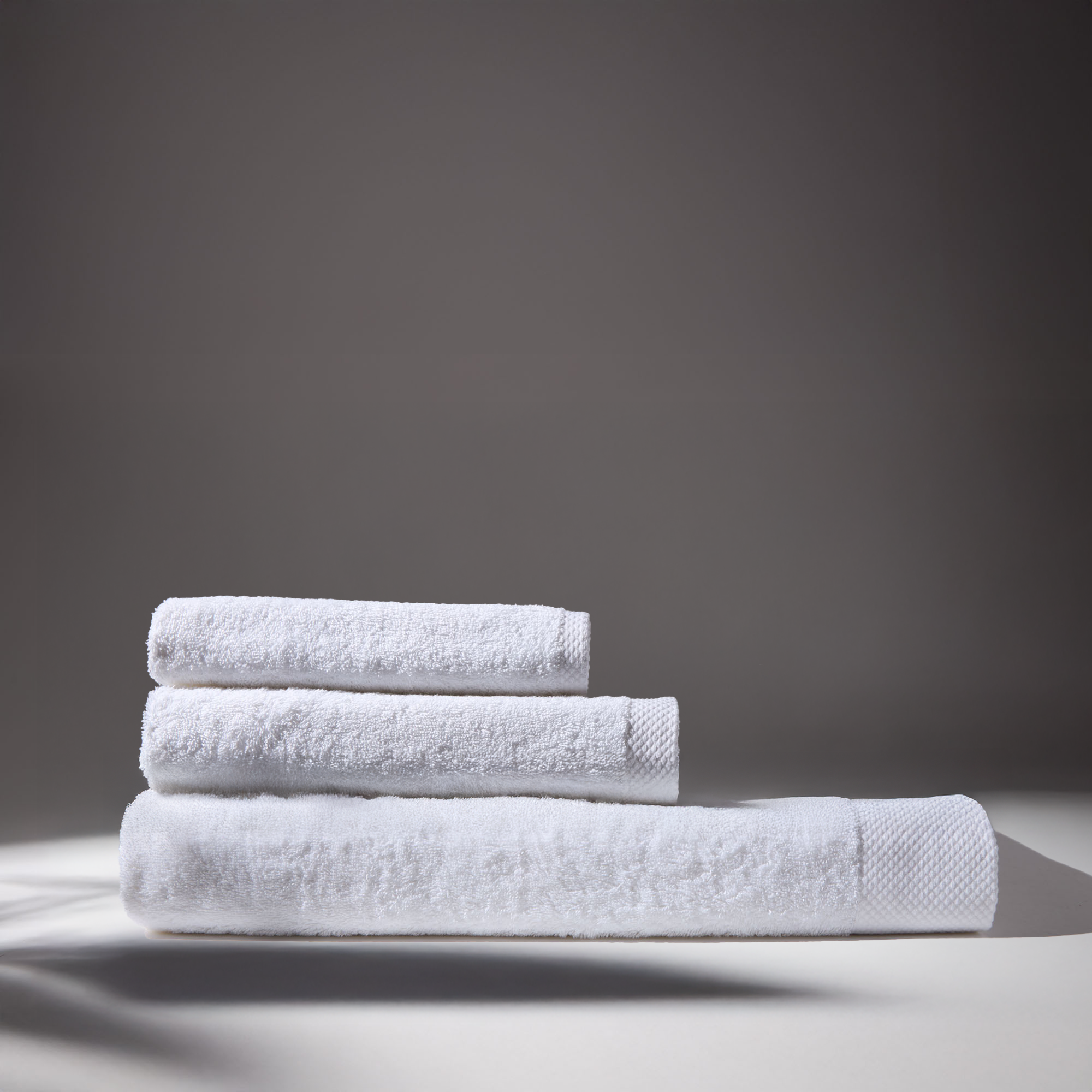 Three white towels stacked on a surface, conveying a sense of cleanliness and freshness.