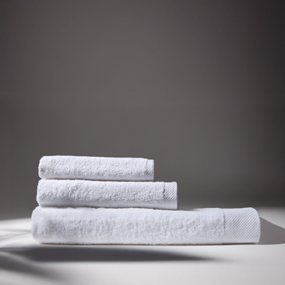 Three white towels stacked on a surface, conveying a sense of cleanliness and freshness.