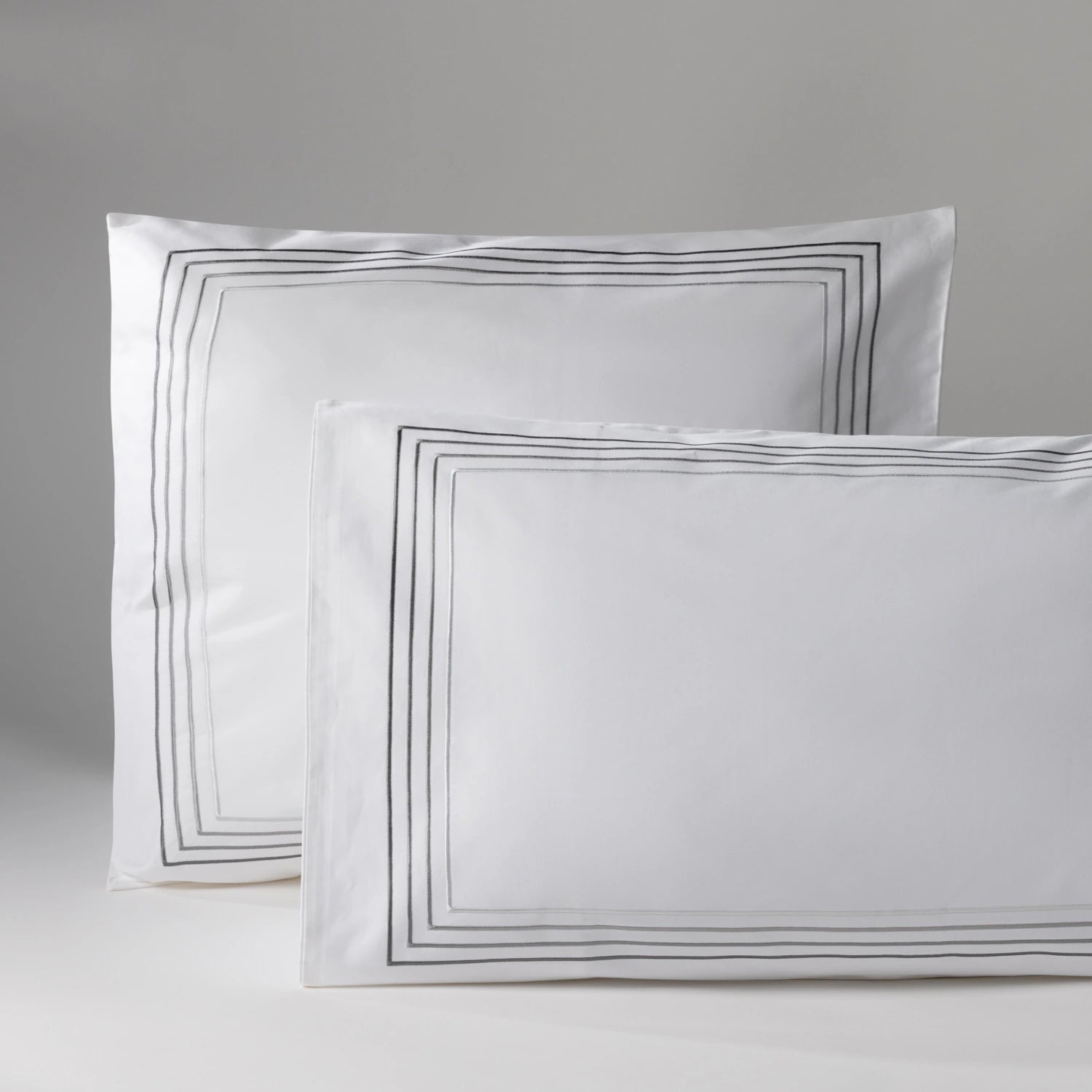 Image of two pillows with white pillowcases and a black frame, on a neutral background. Perfect for decoration or bedtime comfort.