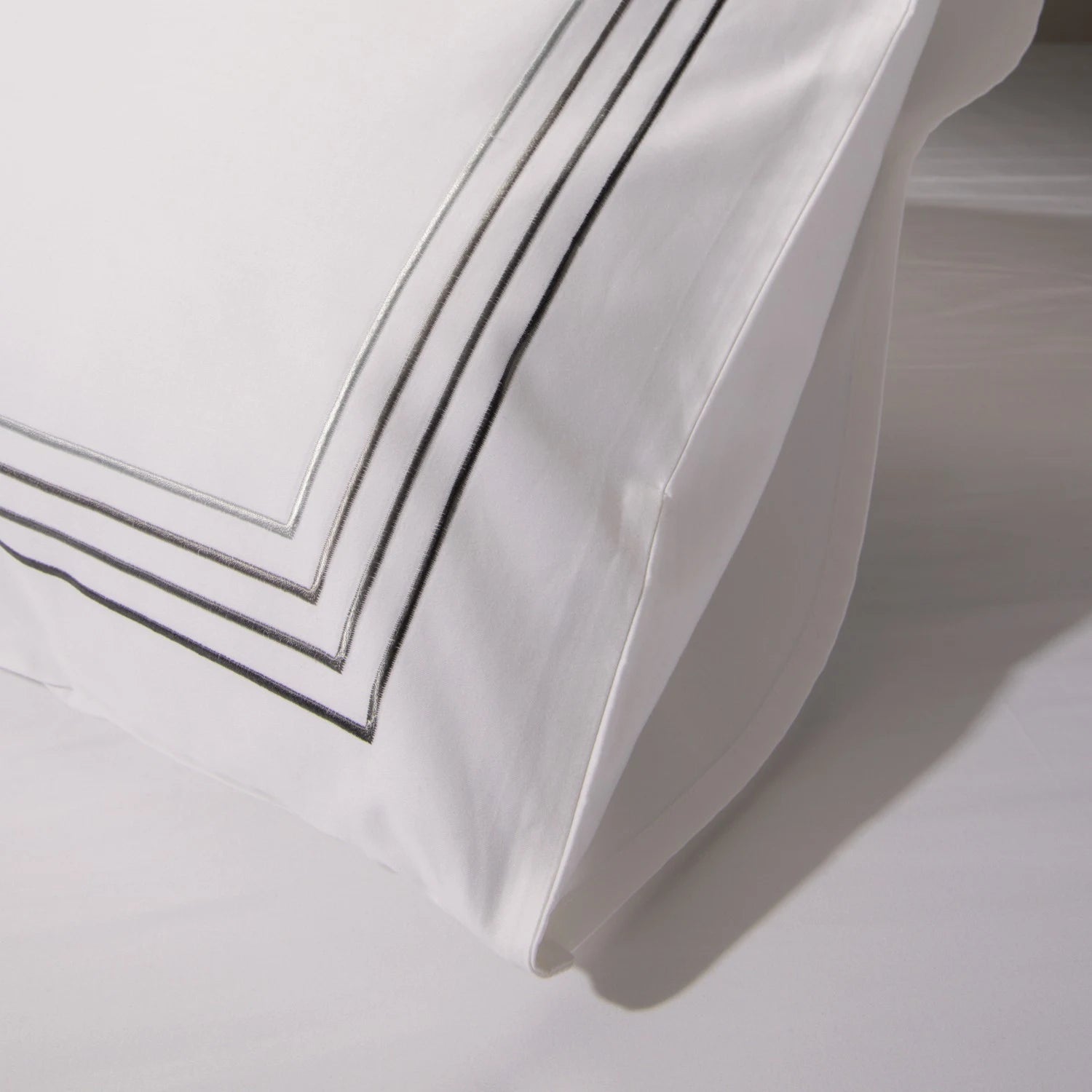 Detailed image of a white pillowcase with a black frame, on a neutral background. Perfect for decoration or bedtime comfort.