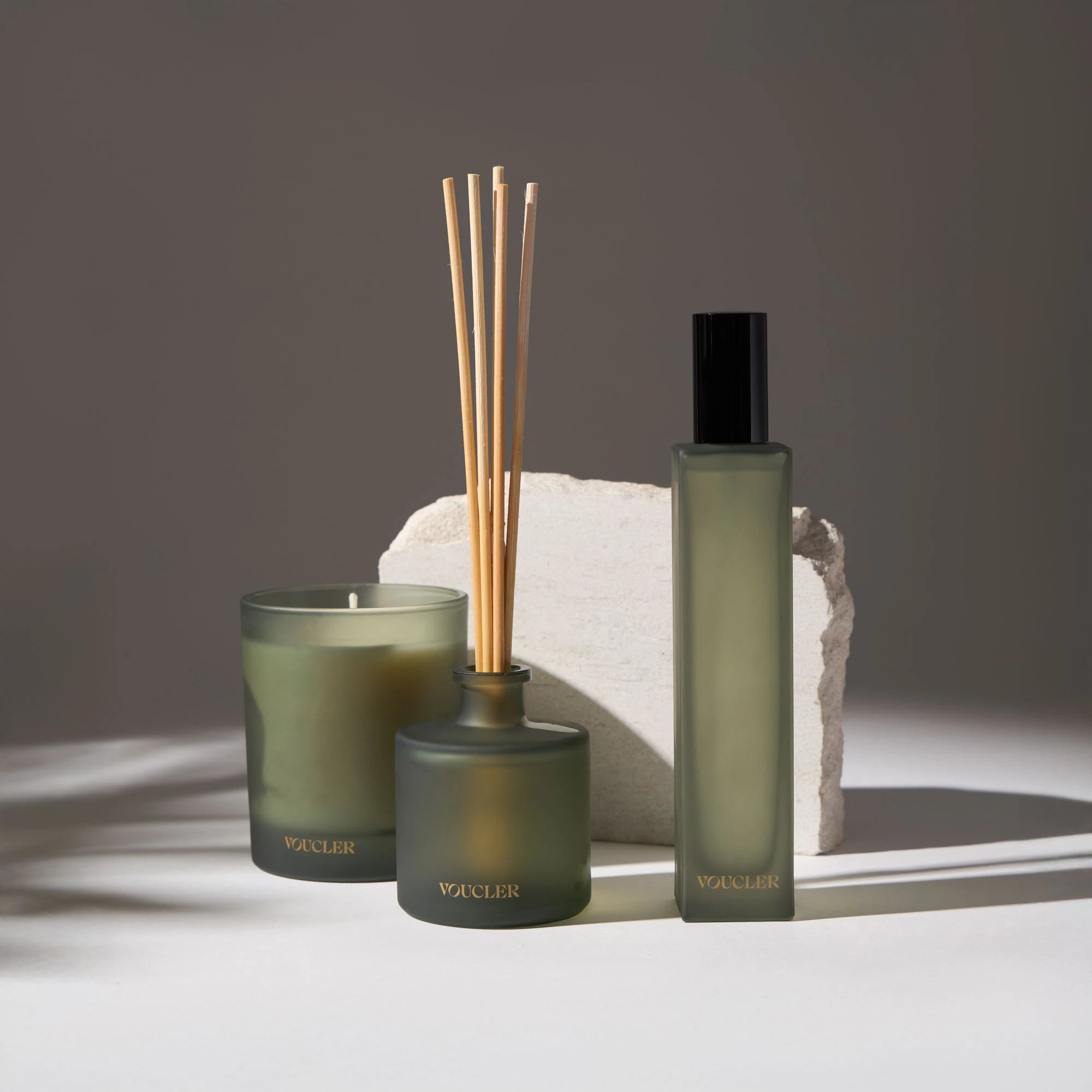 A set of Voucler aromatic products with a candle, diffuser and spray, in a minimalist and elegant setting for home decoration.